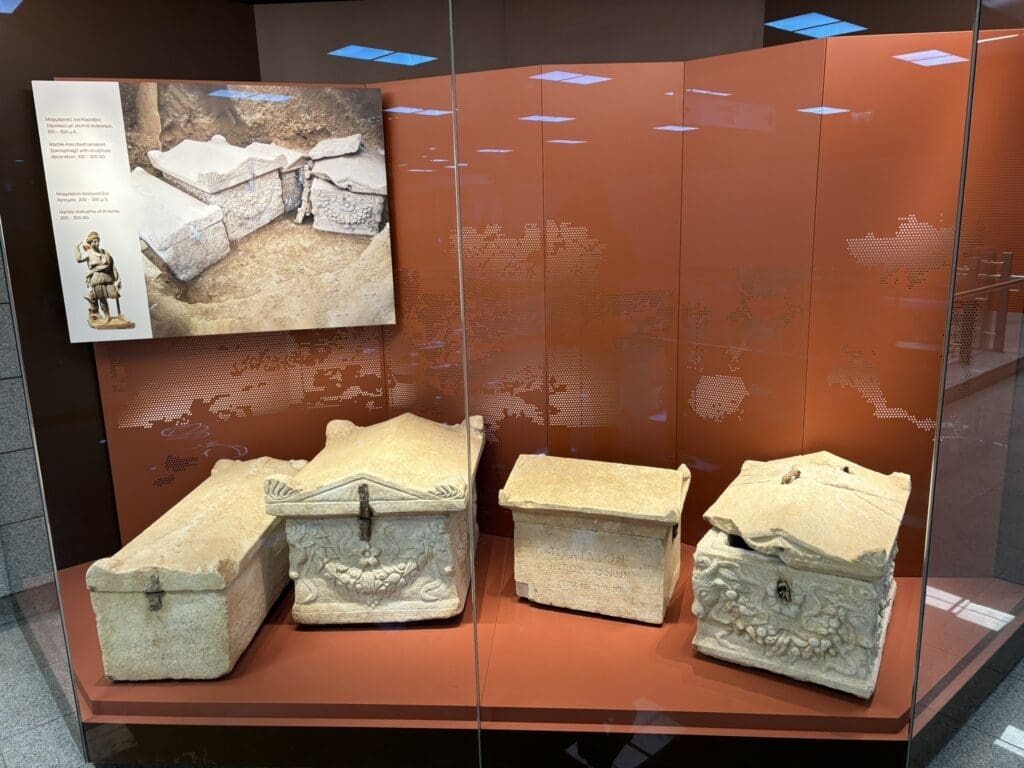 A selection of decorated ossuaries, in a museum display case, discovered at the city’s ancient necropolis and now on display in Sintrivani Metro station. Photo courtesy Mark Wilson.