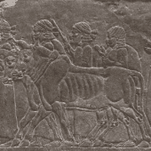Relief detail of panel from Nineveh. Greyish brown scene of oxen dragging a cart with people in it