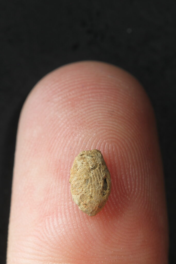 Tiny clay bead with child's fingerprint placed on a modern fingertip