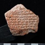 pentagon-shaped fragment of a cuneiform tablet positioned on a black background. Courtesy Turkish Ministry of Culture and Tourism.