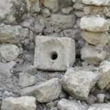 rectangular slab with hole in center, which acted as a toilet seat in antiquity, pictured alongside other stones. Credit: Wikimedia Commons, CC BY-SA 2.0.