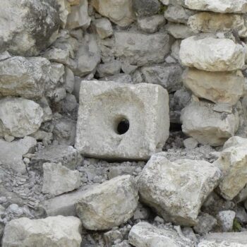 rectangular slab with hole in center, which acted as a toilet seat in antiquity, pictured alongside other stones. Credit: Wikimedia Commons, CC BY-SA 2.0.