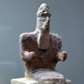 stone statuette of a seated, bearded god with elbows bent to a 90 degree angle. Credit: Wikimedia Coomons, CC BY-SA 4.0.